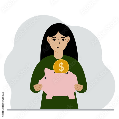Happy woman holds a piggy bank, a coin falls into the piggy bank. The concept of saving finance, savings, investing finances.