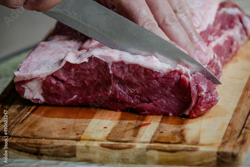 Cutting beef on the table with sharp knife with landscape background.