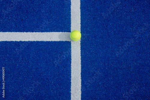 Close-up of a tennis ball on the white line of a paddle tennis court © VicVaz