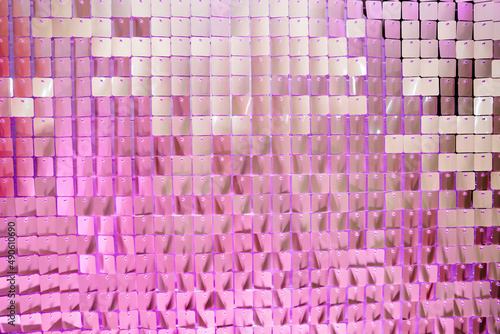 in purple light. Wall Made Of Many Square Sparkling Sequins. Photo Zone