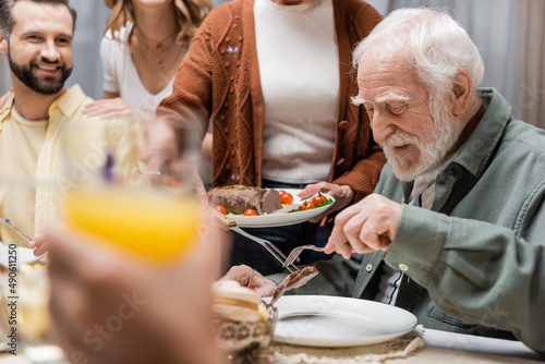 Canvas Print senior woman serving fried meat during easter dinner with family.