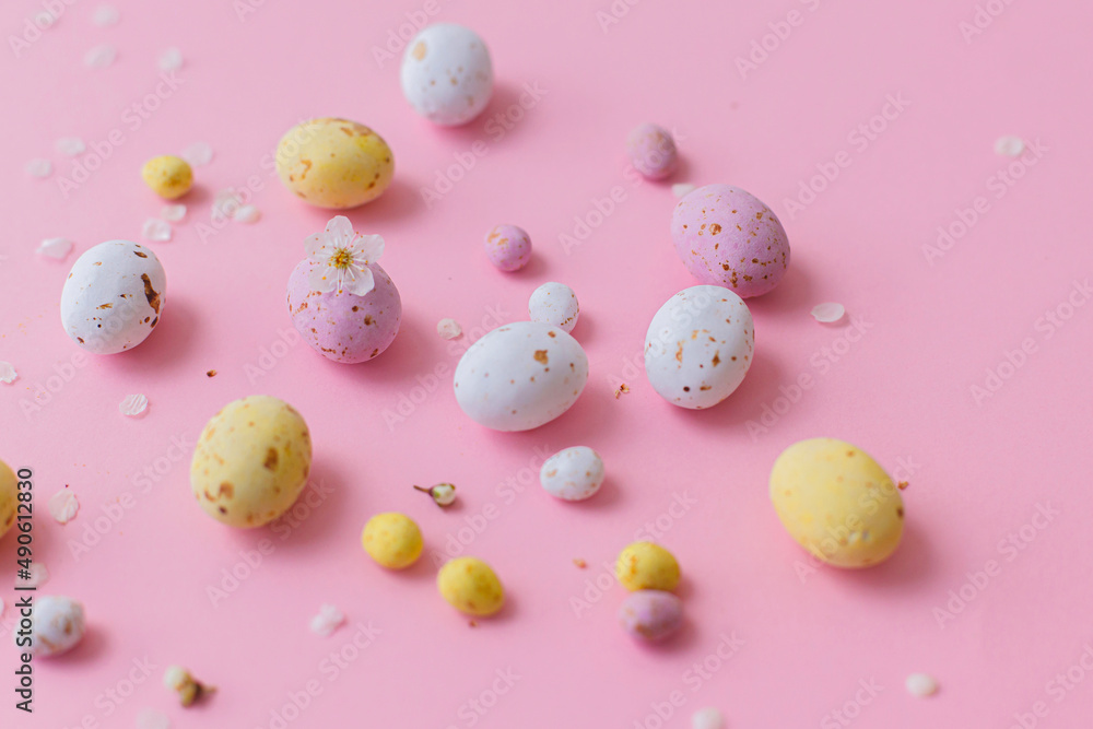 Happy Easter! Colorful Easter chocolate eggs with cherry blossoms on pink background. Stylish tender spring template, creative layout. Greeting card