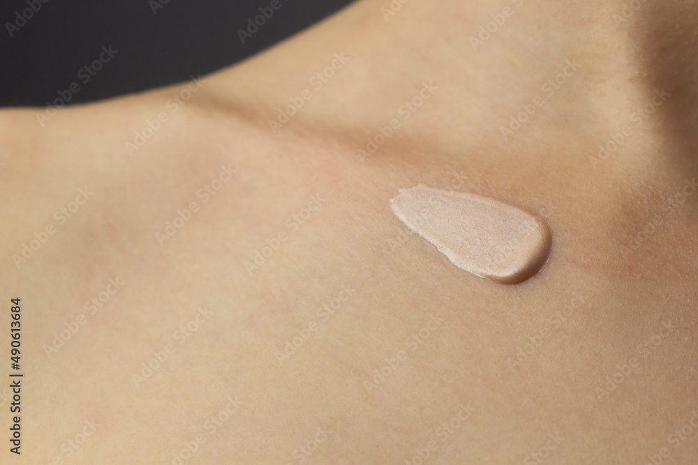 Closeup of a woman applying highlighting lotion to her neck and chest.