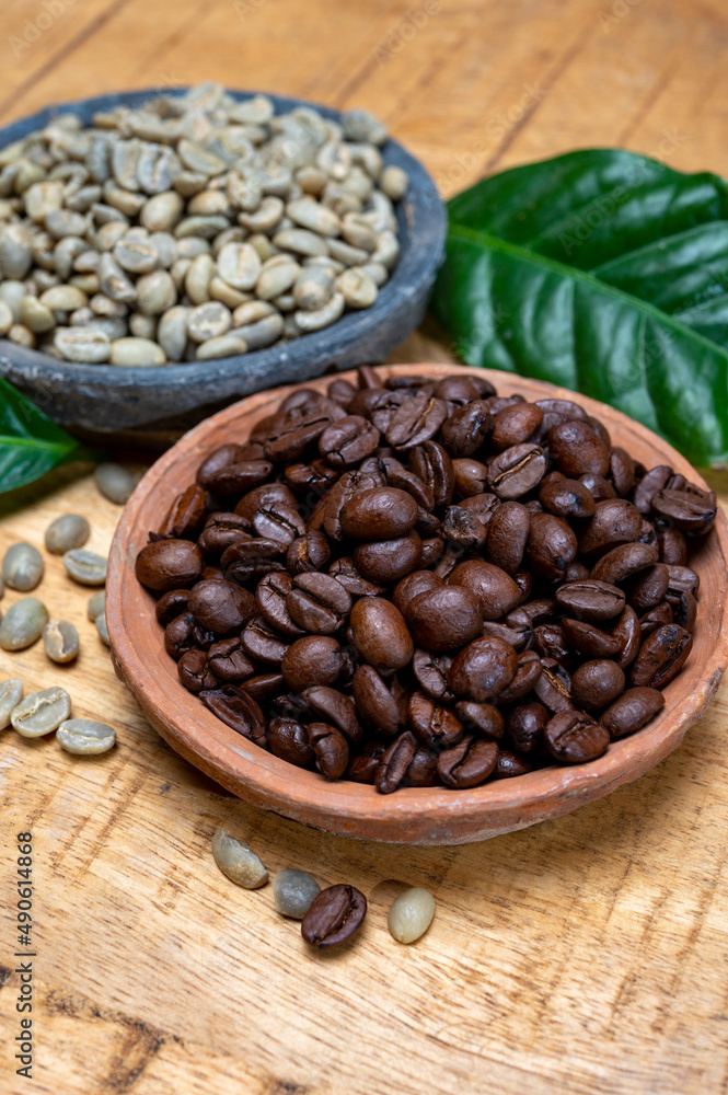Fototapeta premium Green un-roasted and brown roasted coffee beans from Africa coffee producing region, cultivating in Ethiopia, Ivory Coast, Uganda, Kenya, Rwanda and Tanzania
