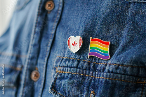 Close up of LGBT pin in the form of a flag with Canada pin is pinned on blue jeans jacket. LGBT rights in Canada concept.