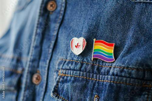 Close up of LGBT pin in the form of a flag with Canada pin is pinned on blue jeans jacket. LGBT rights in Canada concept. photo