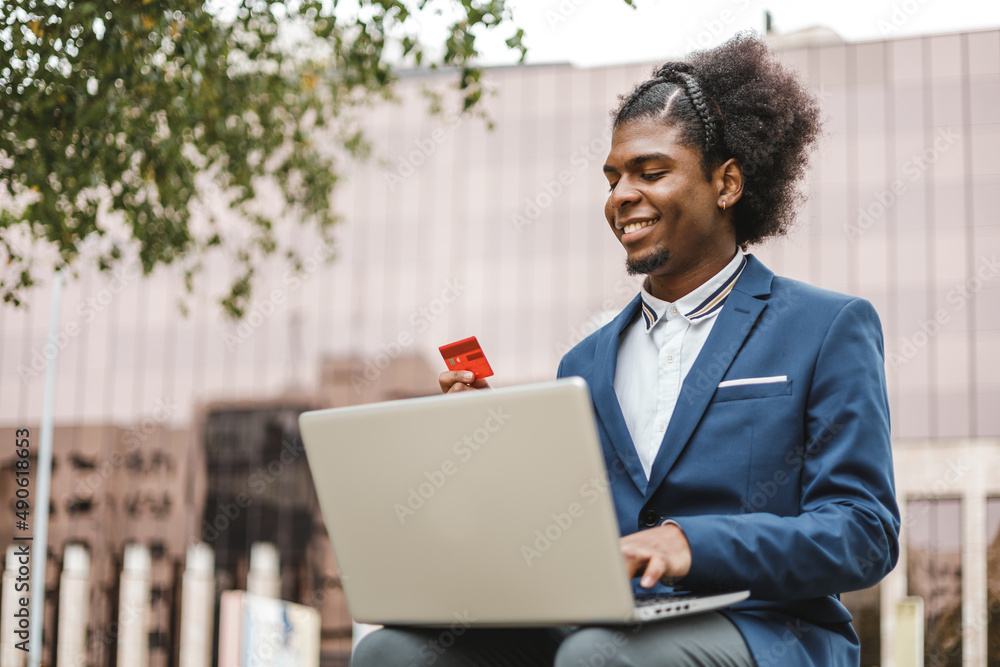 smiling afro businessman using shopping online with credit card smiling afro businessman using shopping online with credit card