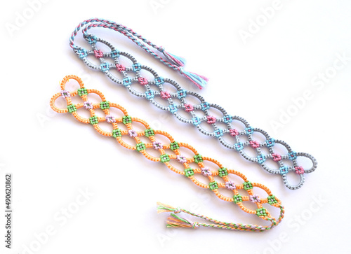 Woven DIY friendship bracelets handmade of embroidery bright thread with knots on white background