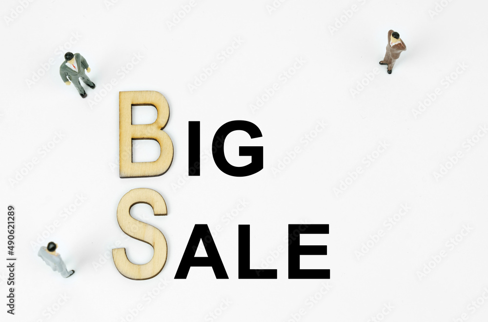 On a white background, figures of businessmen, wooden letters and the inscription - BIG SALE On a white background, figures of businessmen, wooden letters and the inscription - BIG SALE