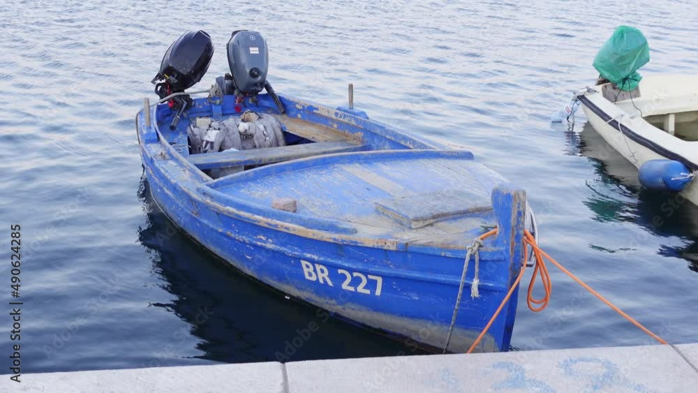 Video Stock An old wooden fishing boat with worn blue paint floats on ...