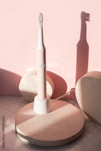 New modern ultrasonic toothbrush. Dental care supplies on cylinder podium on pink pastel background. Oral hygiene, dental and gum health, healthy teeth. Dental products 