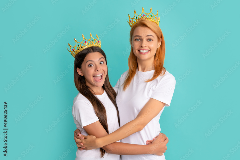 Happy woman and girl child in crowns hug smiling blue background, mother - obrazy, fototapety, plakaty 