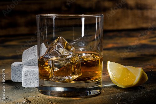 glass of whiskey with ice and lemon. cooling cubes on a dark background.