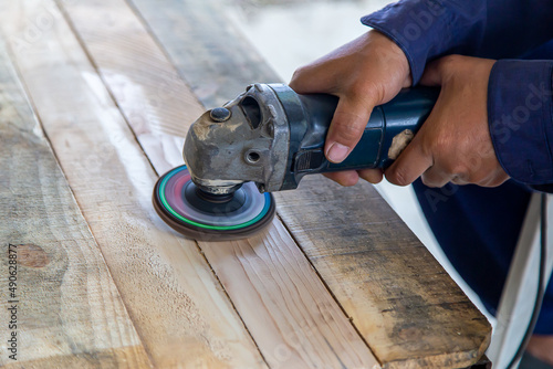 Carpenter polishing pinewood with sander machine