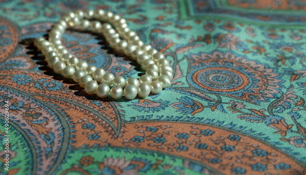 Necklace of natural pearls on a colorful paisley silk scarf Necklace of natural pearls on a colorful paisley silk scarf