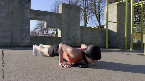 Young lean woman doing pushups outdoors Slider shot track left  photo