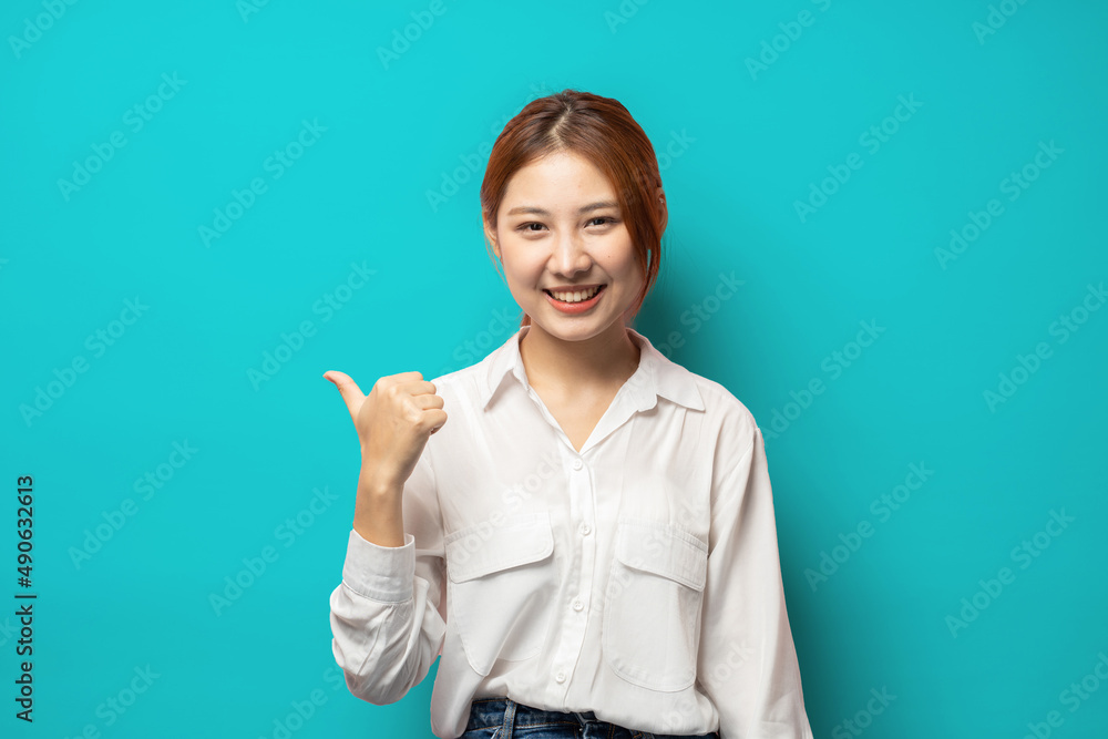 Confident young woman with assured smile pointing left at copy space logo, showing good deal, recommending product, blue background. Confident young woman with assured smile pointing left at copy space logo, showing good deal, recommending product, blue background.