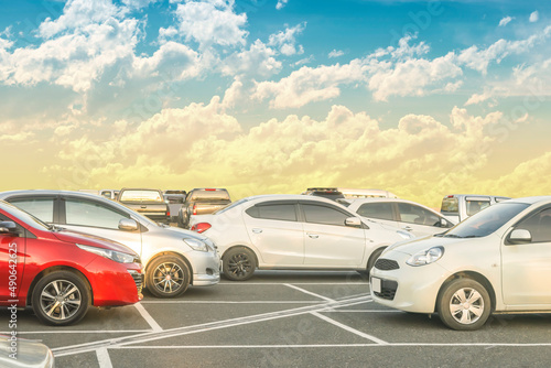 Car parked in large asphalt parking lot with beautiful cloud and sunset sky background © merrymuuu