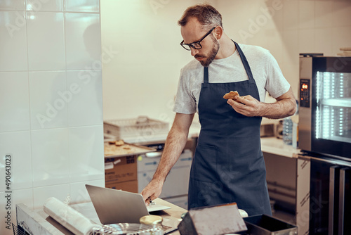 Male worker in apron using notebook in cafe