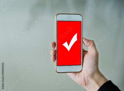 Closeup of hand holding smartphone with vote button on the screen