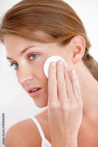 Skincare and beauty. A lovely young woman applying makeup to her cheek with a cotton pad.
