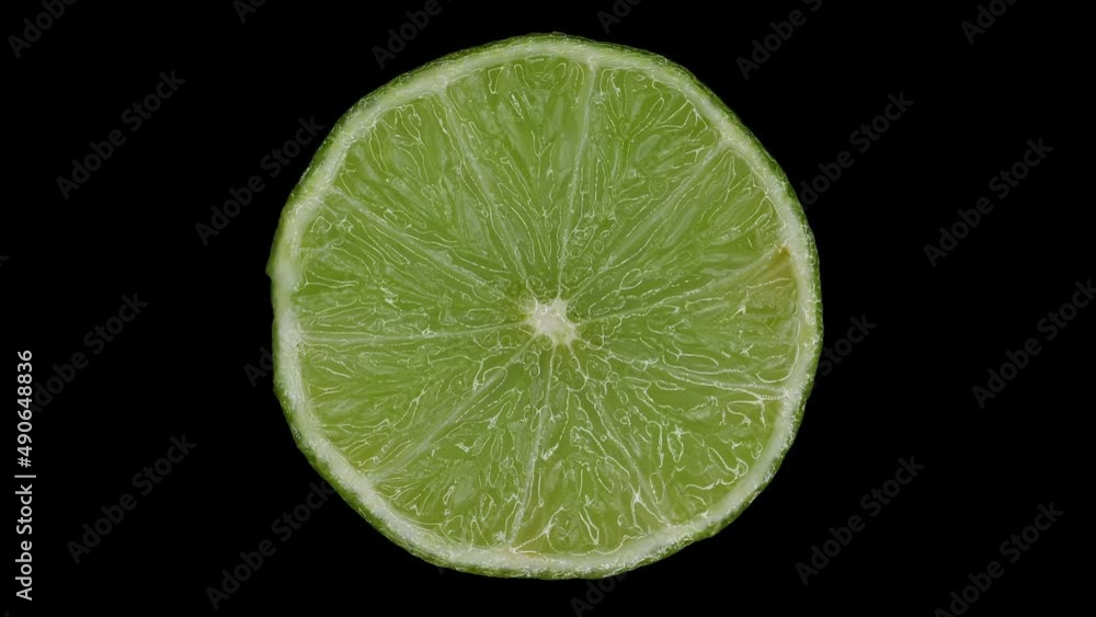 Slice Of Lime Rotating In Black Background. close up, studio shot Slice Of Lime Rotating In Black Background. close up, studio shot