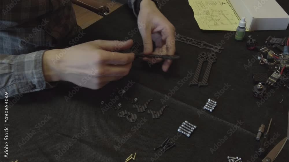 Assembly of carbon frame for FPV quadcopter, 5 inches, black frame on the table, four beams, constructor, bolts, nuts. Assembly of carbon frame for FPV quadcopter, 5 inches, black frame on the table, four beams, constructor, bolts, nuts.