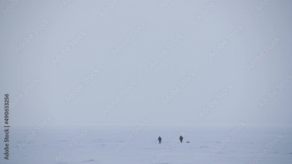 Panoramic view two people walking across the snow-covered Baltic sea Panoramic view two people walking across the snow-covered Baltic sea