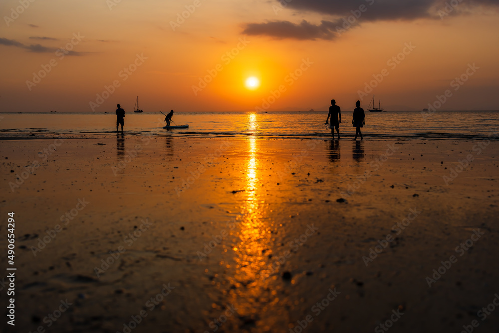 Sunset at beach with silhouette of people enjoying the sea and sunset sky.