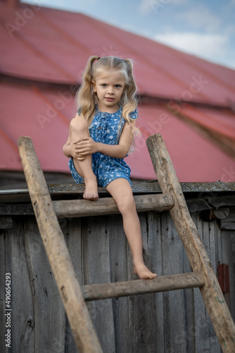 Beautiful little girl model sitting on the stairs on the roof