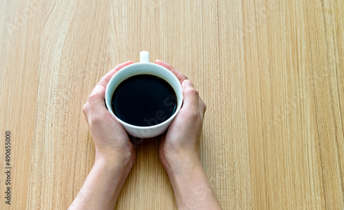 Female hands holding cup of coffee on wooden table