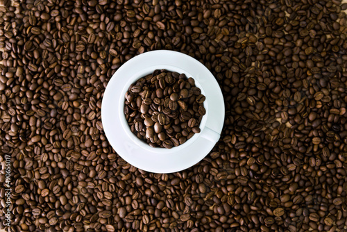Coffee beans in cup and on table for background