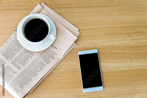 Newspapers, coffee and smartphone on wooden table with top view