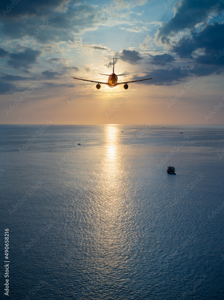 Airplane flying over tropical sea atduring sunset,copy space for text.
