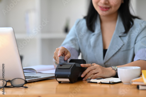 Smiling young woman payment with a credit card through terminal.