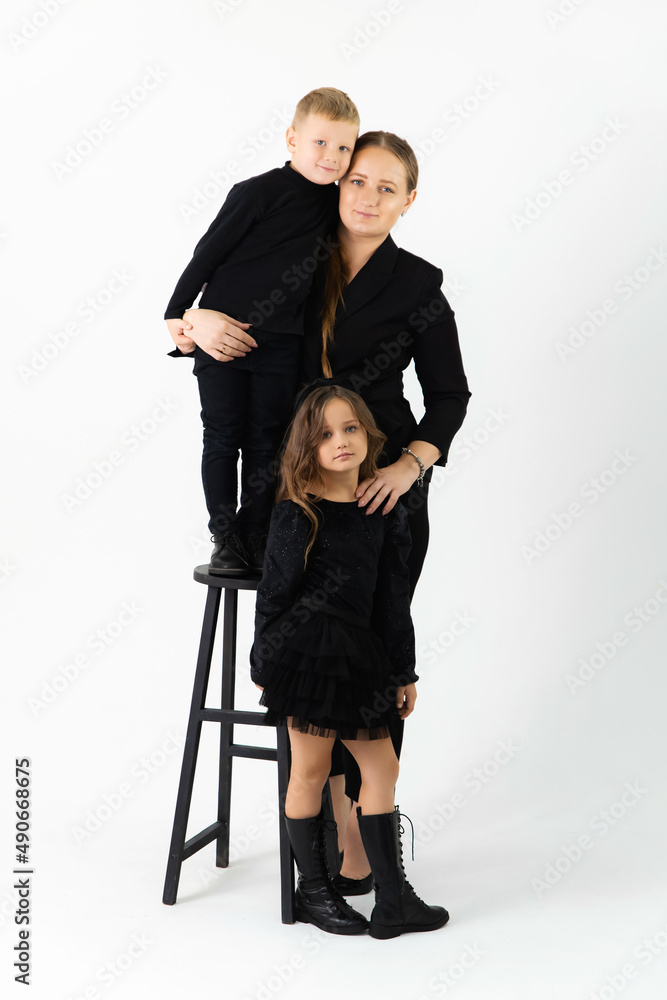 Portrait of a young mother and little preschooler children hugging and to looking at camera laughing and posing together Portrait of a young mother and little preschooler children hugging and to looking at camera laughing and posing together