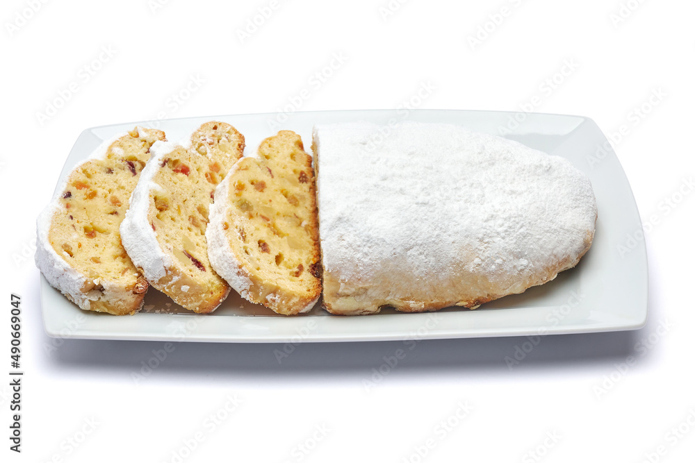 Sliced Traditional Christmas stollen cake with marzipan and dried fruit isolated on ceramic plate