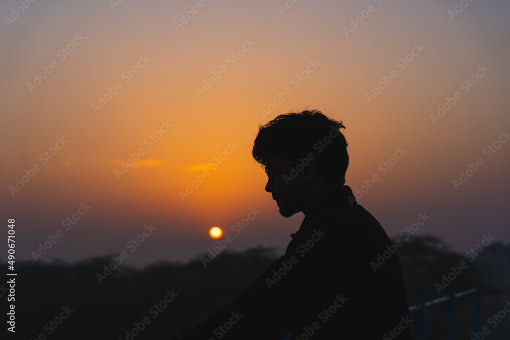 Silhouette of a young boy wearing specs enjoying the beautiful sunset. Silhouette of a young boy wearing specs enjoying the beautiful sunset.