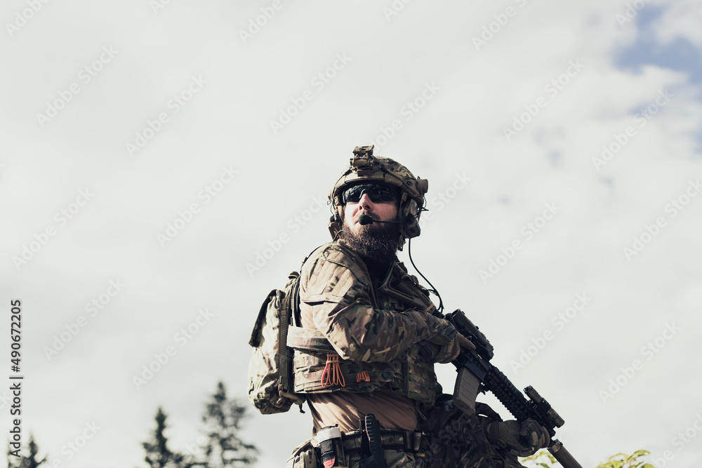 War concept. A bearded soldier in a special forces uniform fighting an enemy in a forest area. Selective focus 