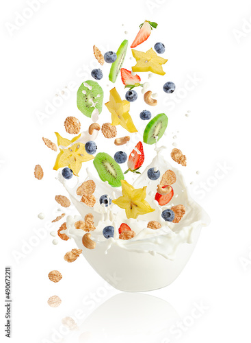 Fresh fruits, berries, corn flakes and nuts falling into the bowl with splashing milk. Healthy muesli breakfast concept.