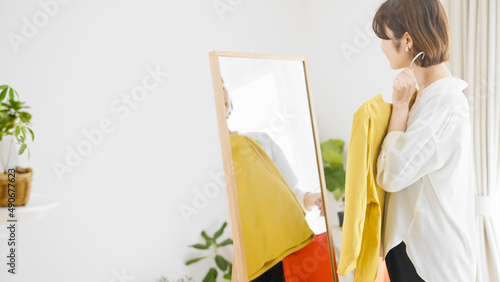 鏡の前で服選びをしている若い女性 ファッションイメージ