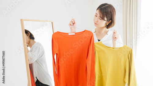 鏡の前で服選びをしている若い女性 ファッションイメージ