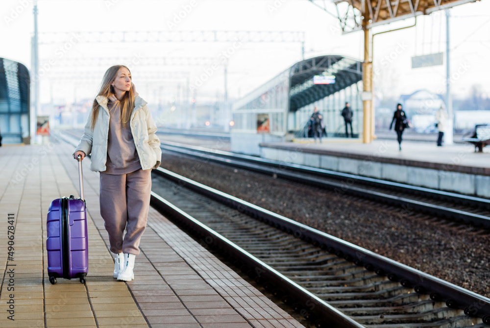 Fototapeta premium A young woman stands on the platform and waits for the train