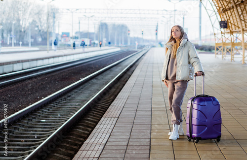 A young woman stands on the platform and waits for the train