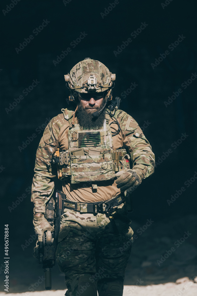 A bearded soldier in a special forces uniform walks through an abandoned building after a successful mission. Selection focus A bearded soldier in a special forces uniform walks through an abandoned building after a successful mission. Selection focus