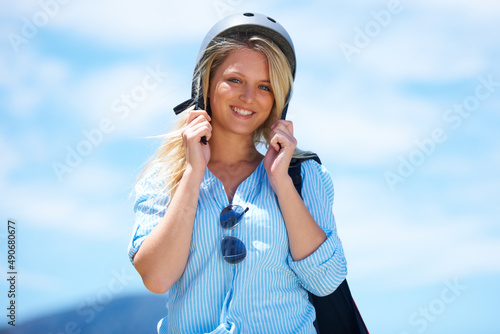 Ready for skydiving fun. Beautiful woman putting on a skydiving helmet outdoors.