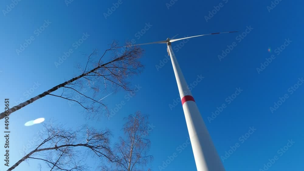 a wind turbine timelapse turning in front of a sunny tree winter sky a wind turbine timelapse turning in front of a sunny tree winter sky