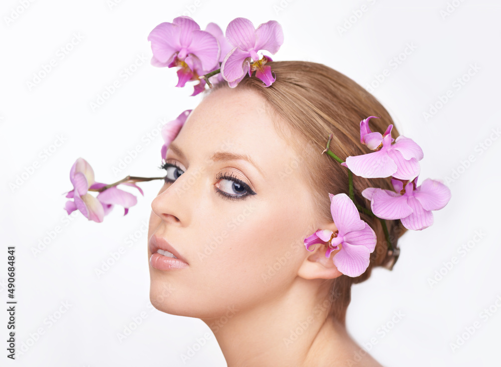 Youthful beauty in full bloom. Studio portrait of a gorgeous young woman with pink orchids in her hair.