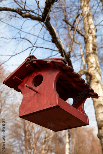 Foto Red wooden birdhouse hanging on a tree branch.