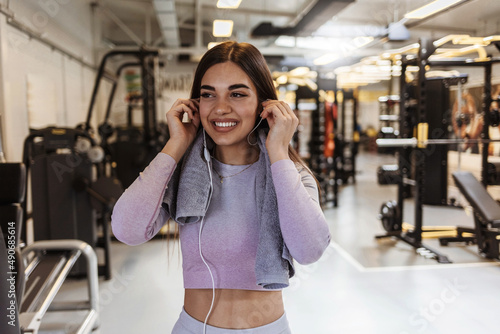 Shot of a sporty young woman listening to music while exercising in a gym. Portrait of a happy woman using earphones at the gym